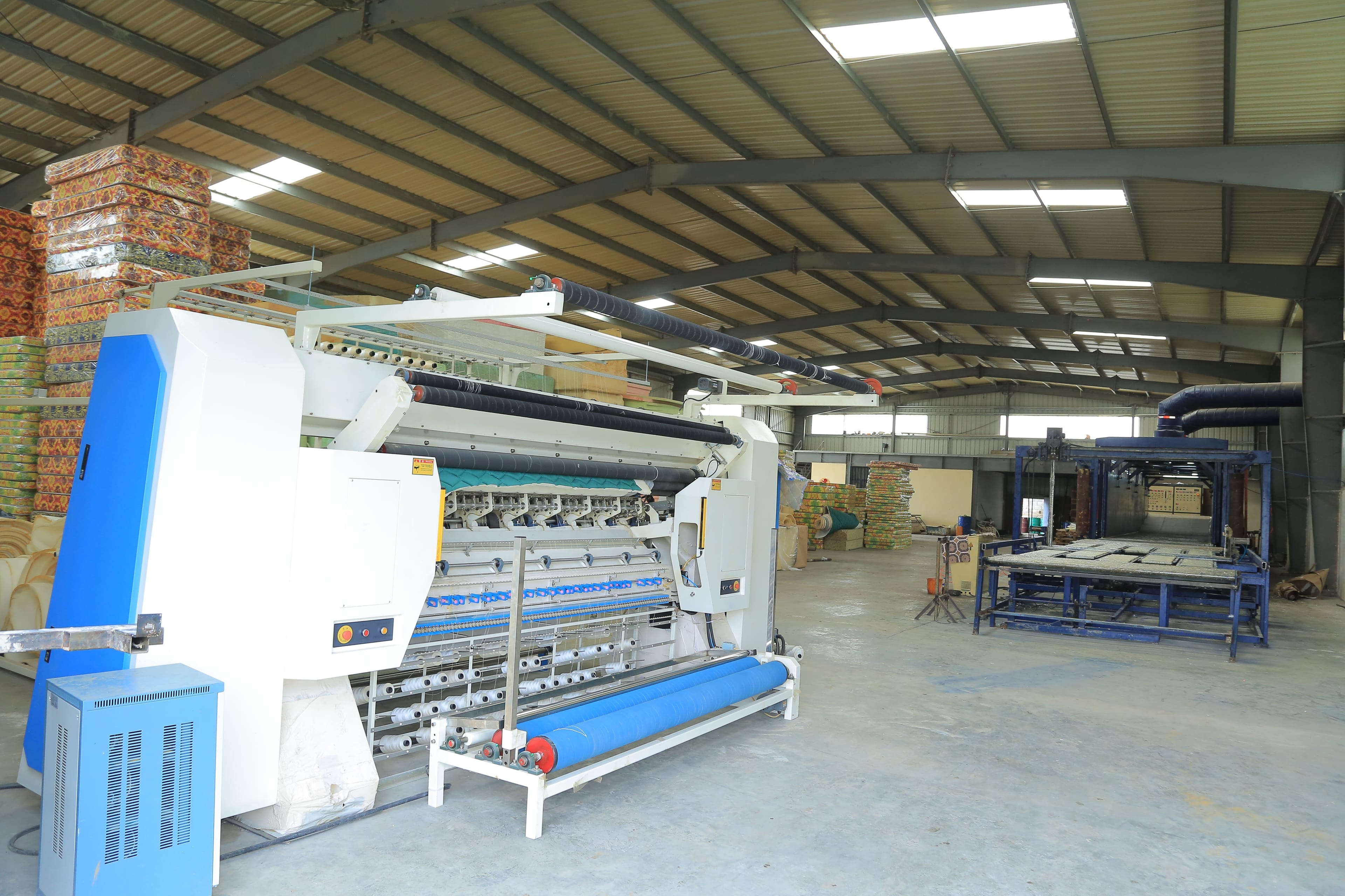 Quilting machine stitching a design into a mattress layer.