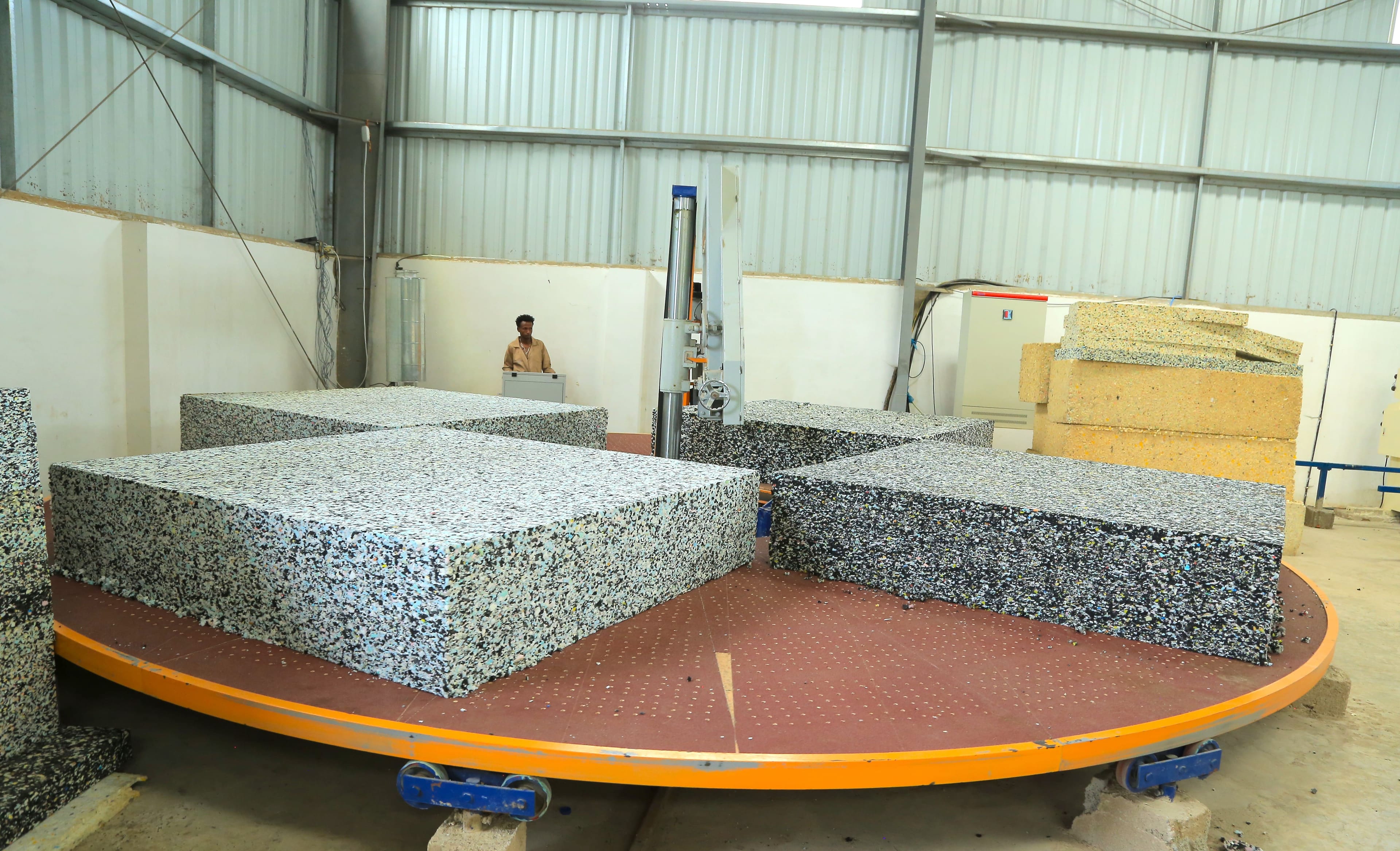 Bonded foam blocks loaded onto an automatic circular cutting machine.